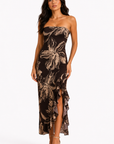 Woman wearing a strapless floral dress with a slit on a white background