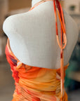 Mannequin wearing a colorful dress with orange and yellow gradient on a blurred indoor background