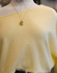 Mannequin wearing a yellow top with a necklace and belt